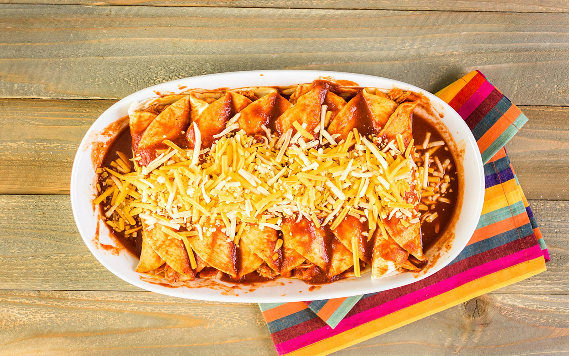 Delicious Enchilada Platter Topped with Cheddar Cheese. Wallpaper