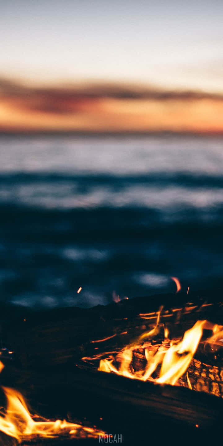 En bålplads med flammer på stranden. Wallpaper