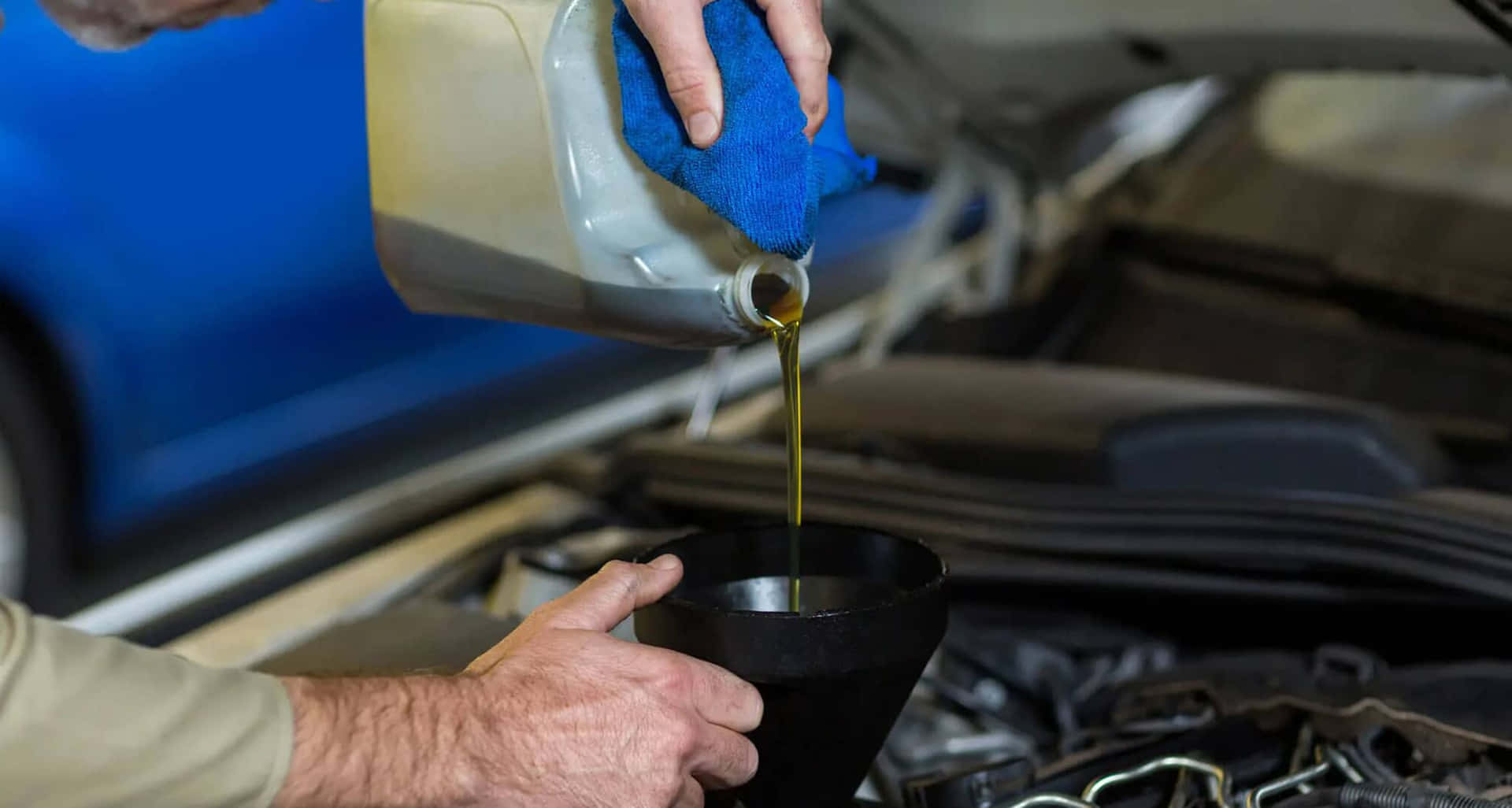 A Man Pouring Oil Into A Car Engine