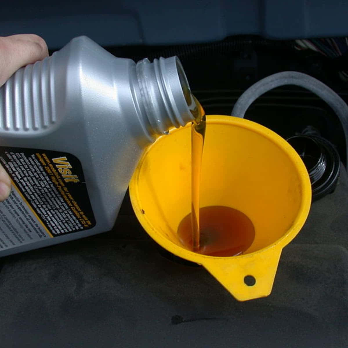 A Person Pouring Oil Into A Yellow Container