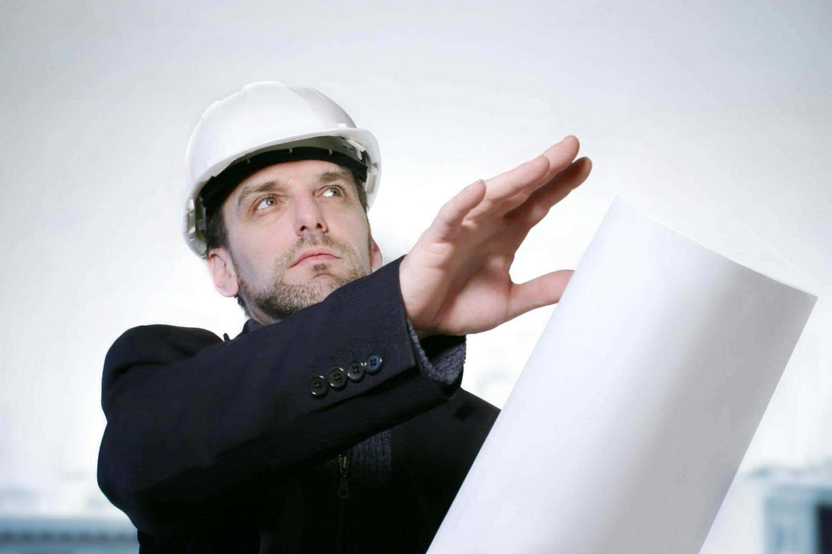A Man In A Hard Hat Is Holding A Piece Of Paper