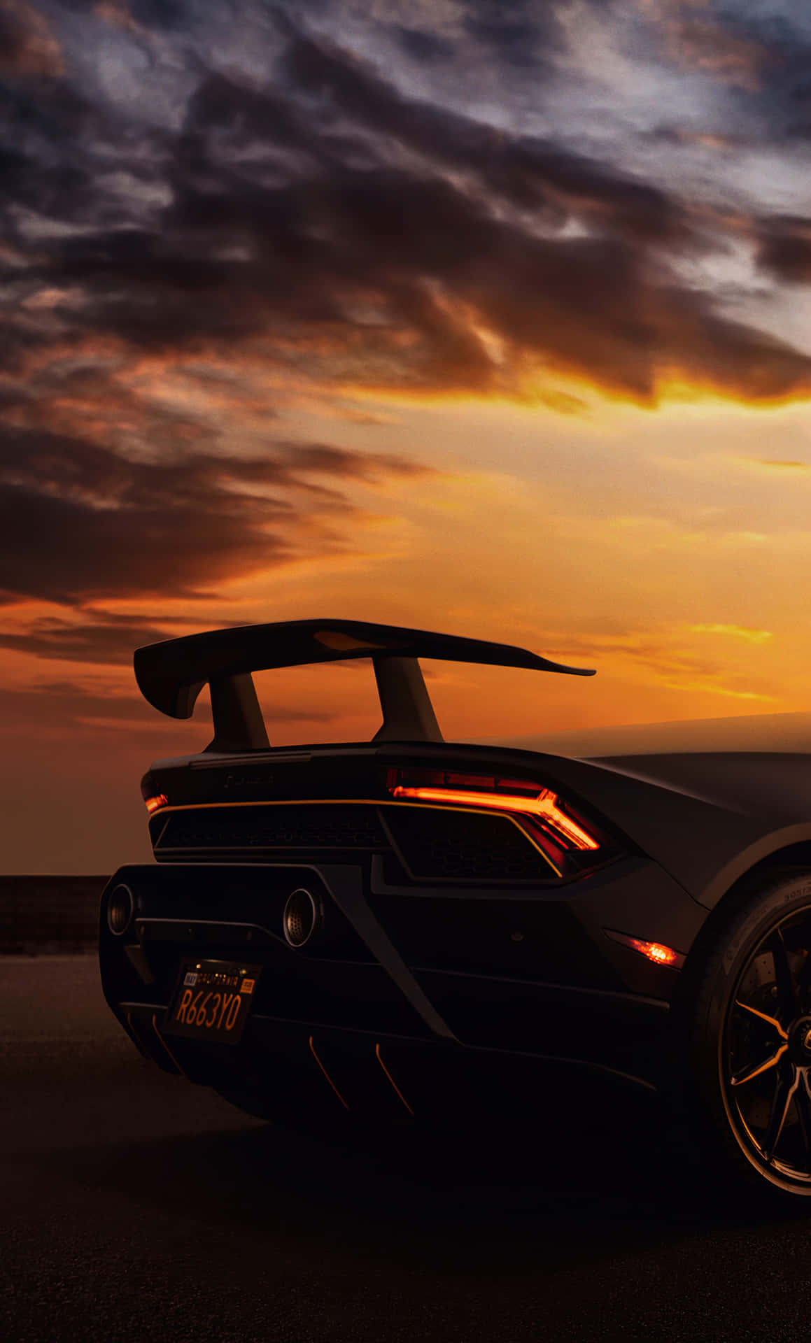 En sort sportsvogn er parkeret i solnedgangen. Wallpaper