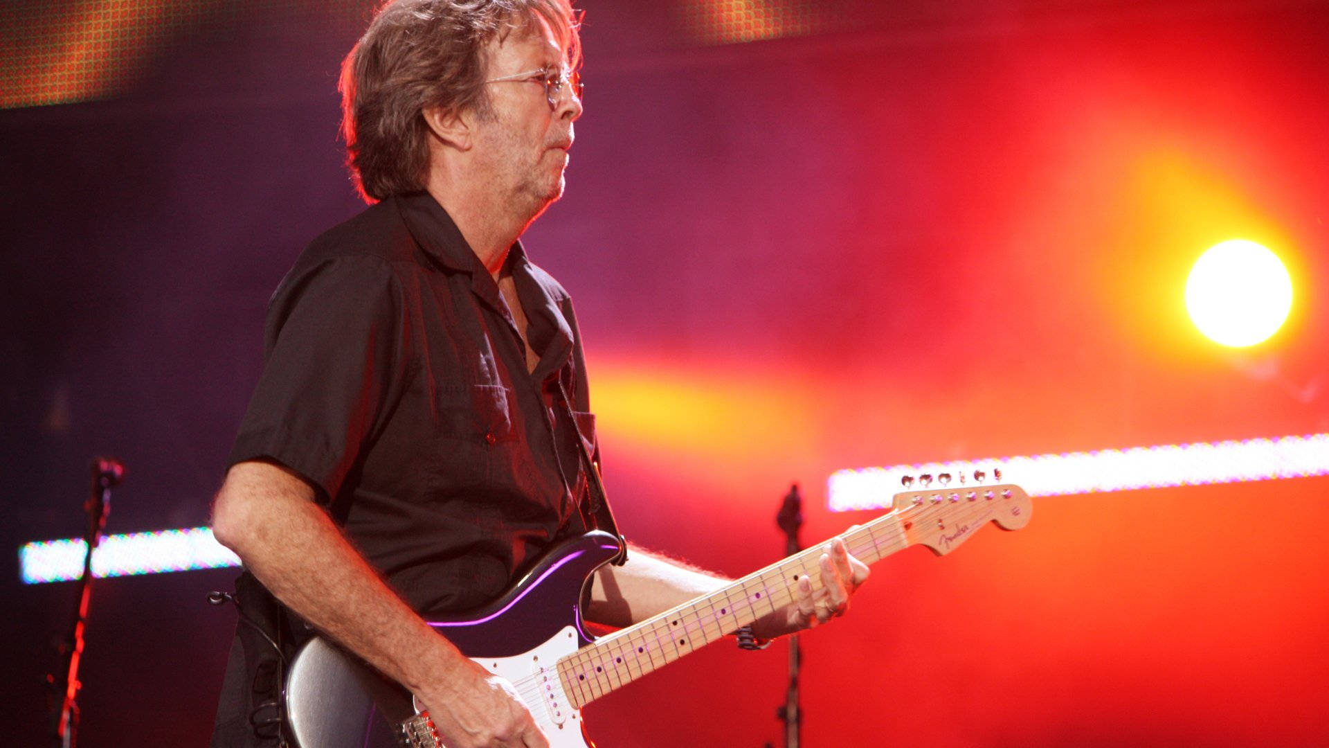 Eric Clapton Against Vibrant Orange Light Wallpaper