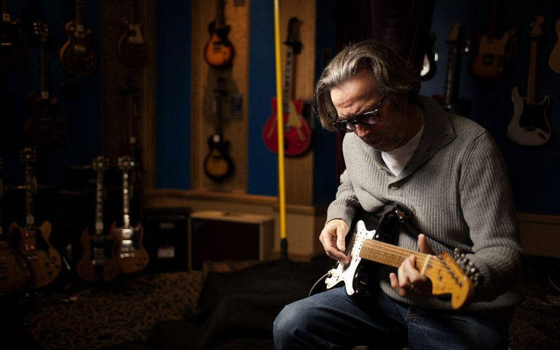 Legendary Musician Eric Clapton in His Guitar Collection Room Wallpaper