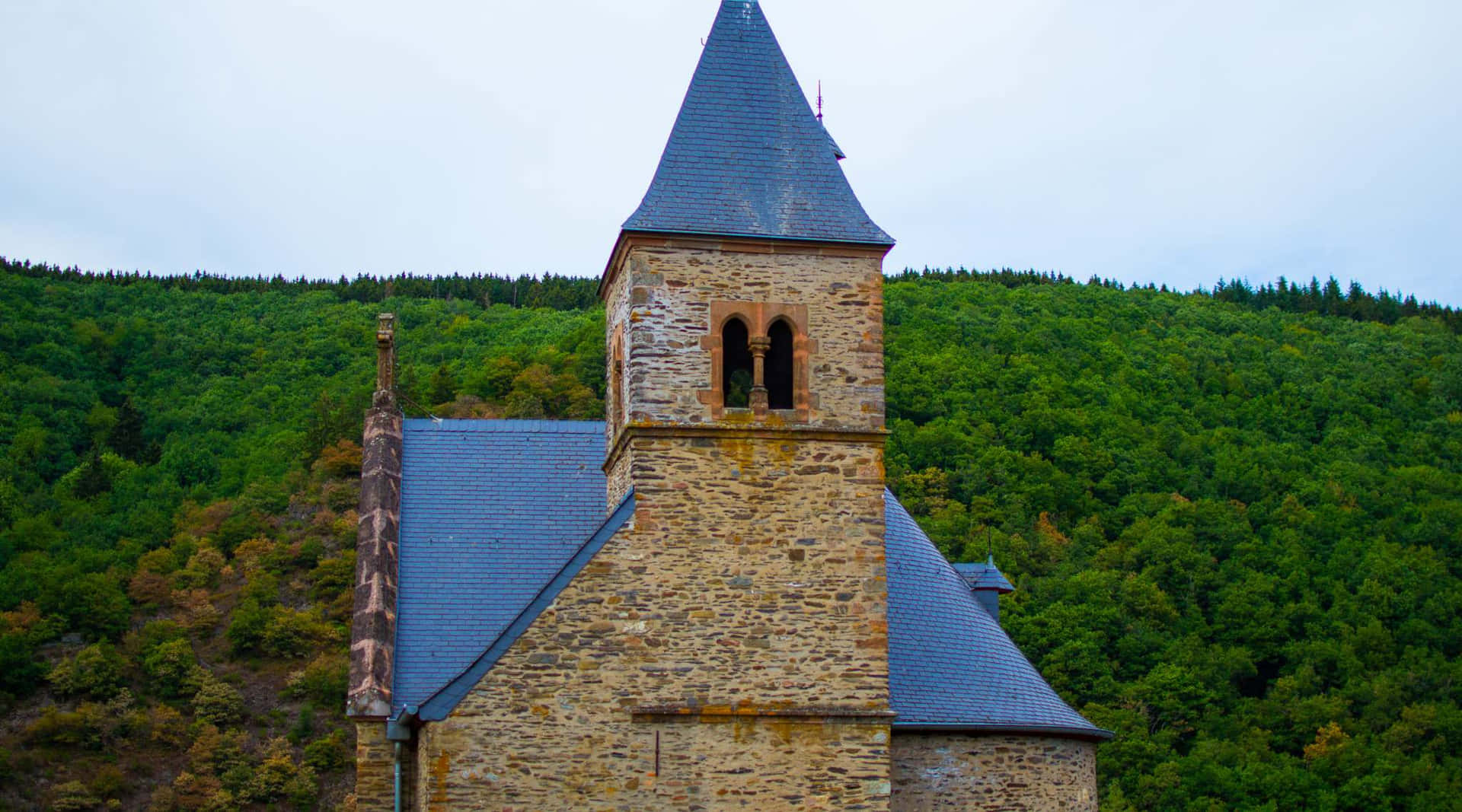 Eschsur Alzette_ Church_ Against_ Forest_ Backdrop Wallpaper