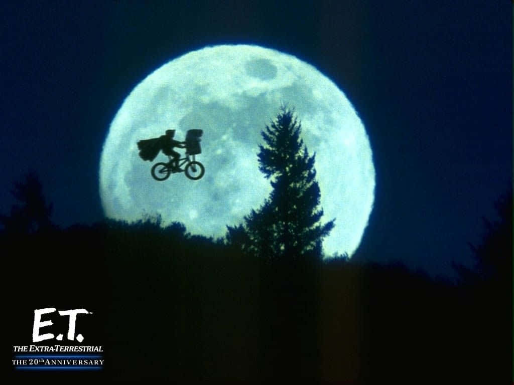 En mand rider på cykel foran en fuldmåne.