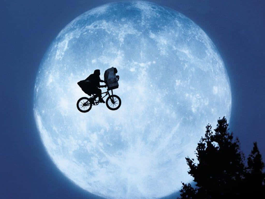 a man riding a bike in front of a full moon