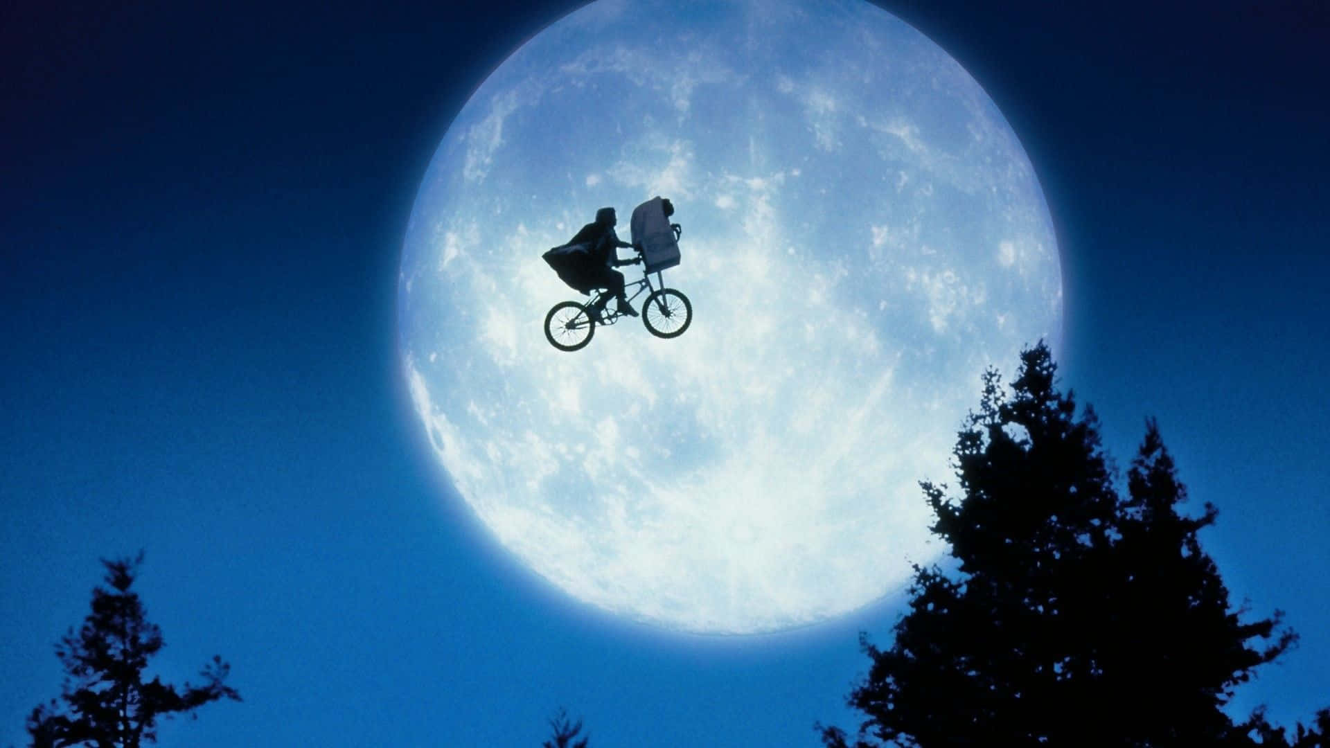 A Man Riding A Bike In Front Of A Full Moon