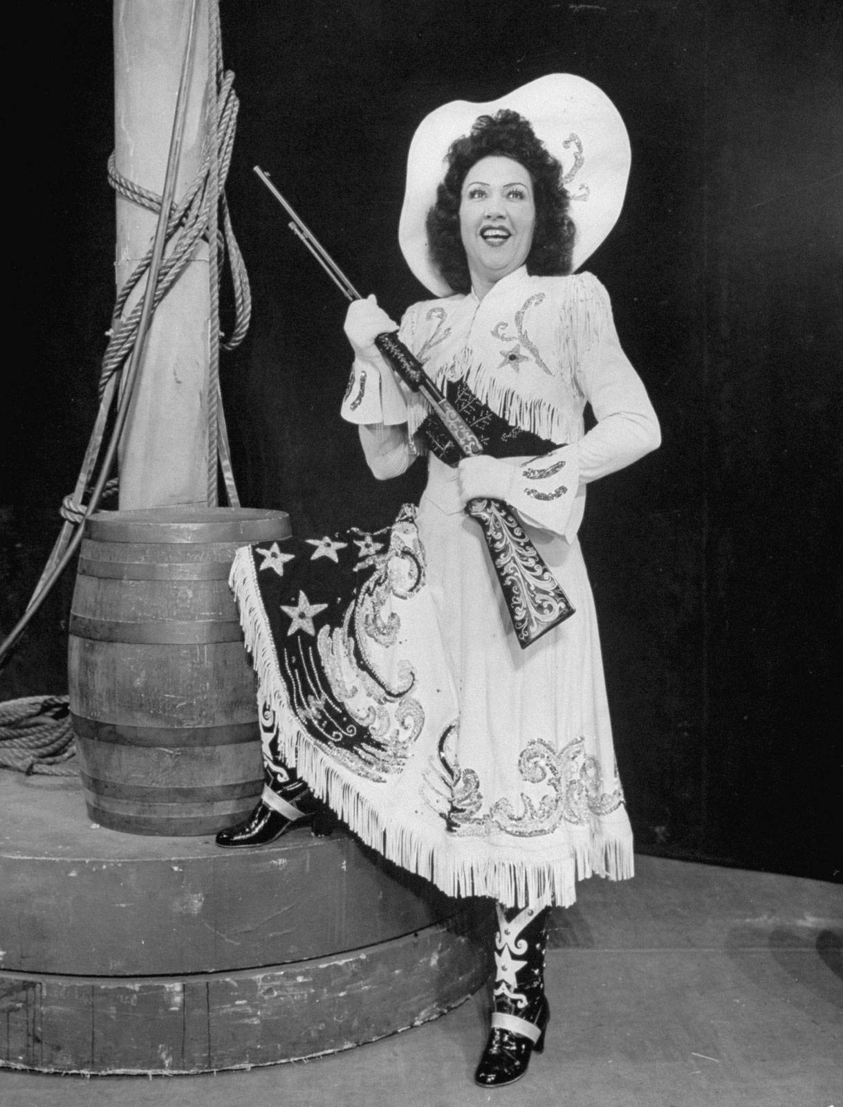 Ethel Merman holder et gevær ved siden af en fiskekar. Wallpaper