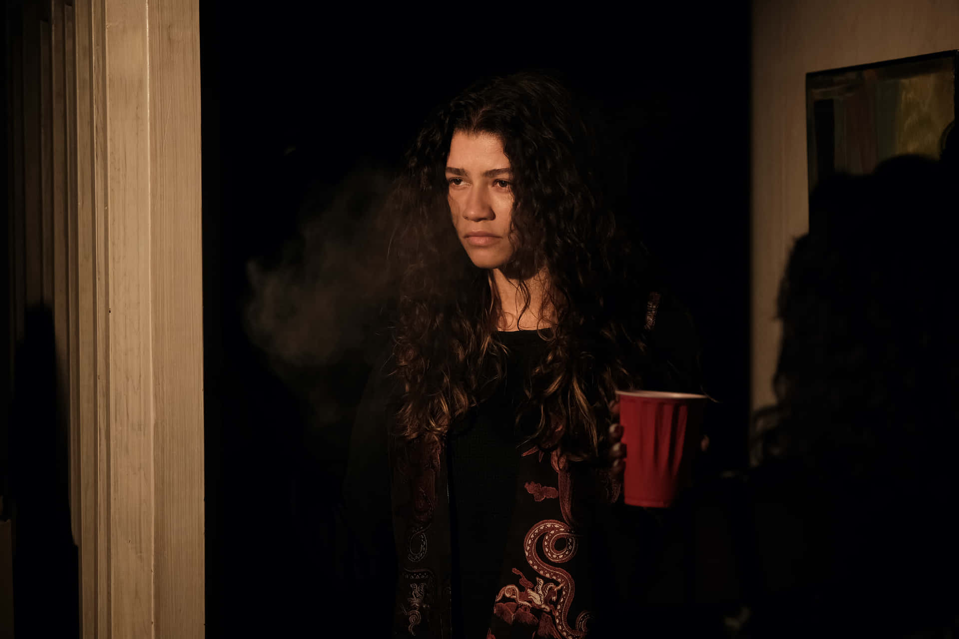 En kvinde holder et glas kaffe i mørket Wallpaper