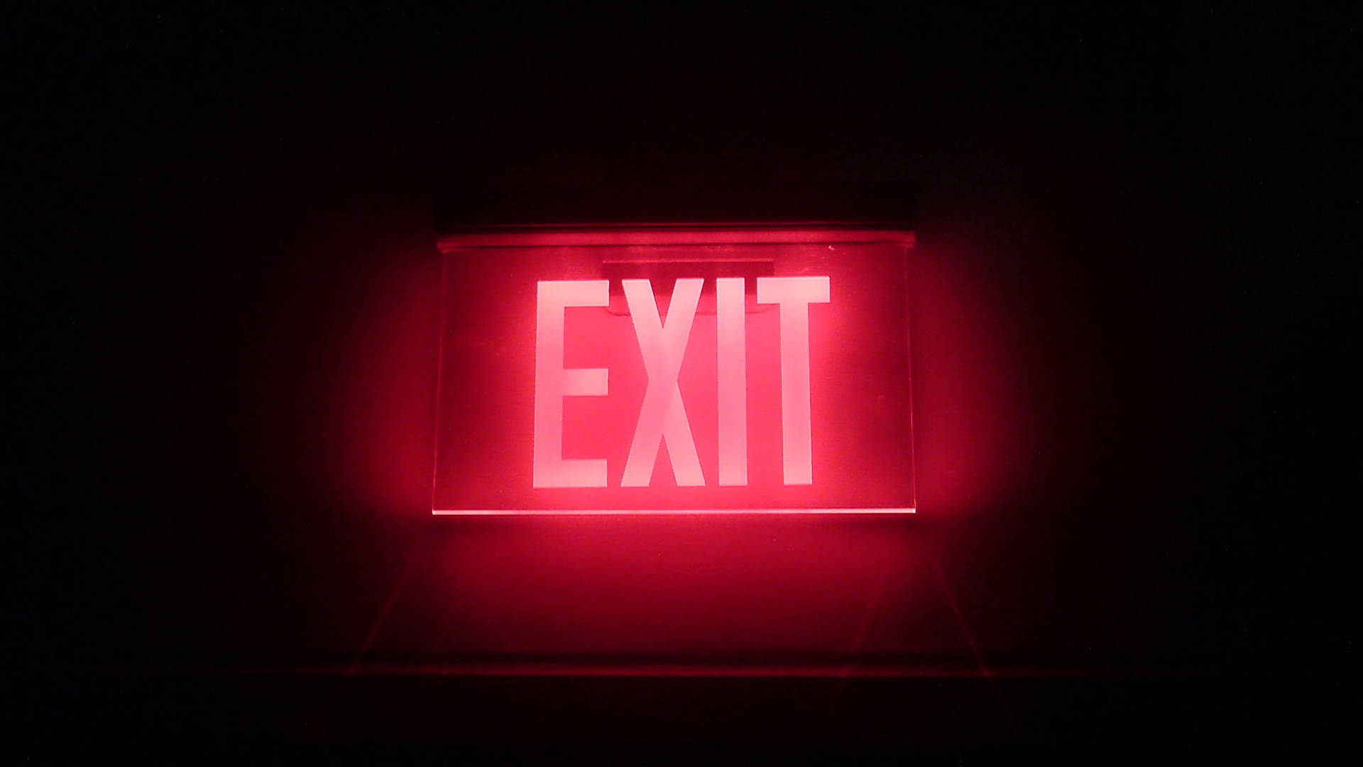 Illuminated Exit Sign Displayed on Black Tablet Screen Wallpaper