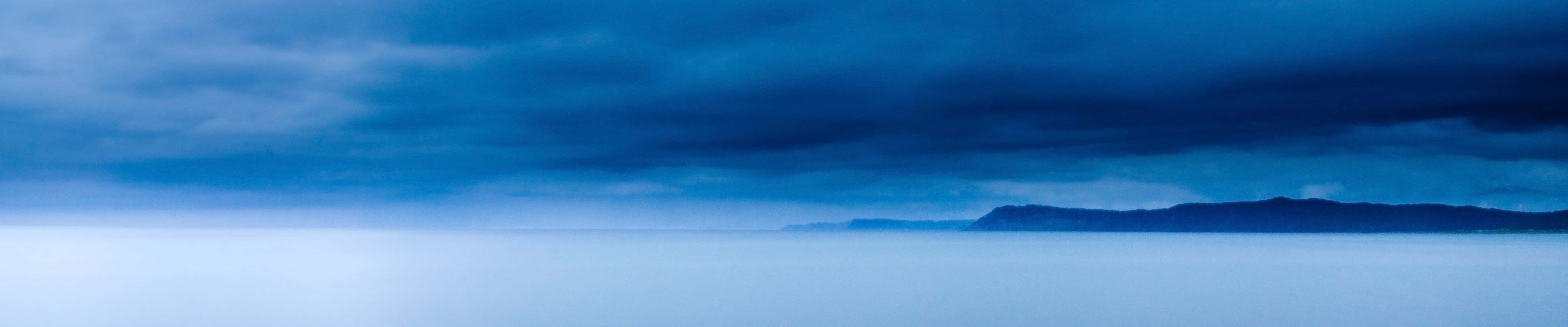 Eindunkler Himmel Über Dem Ozean Mit Bergen Im Hintergrund. Wallpaper