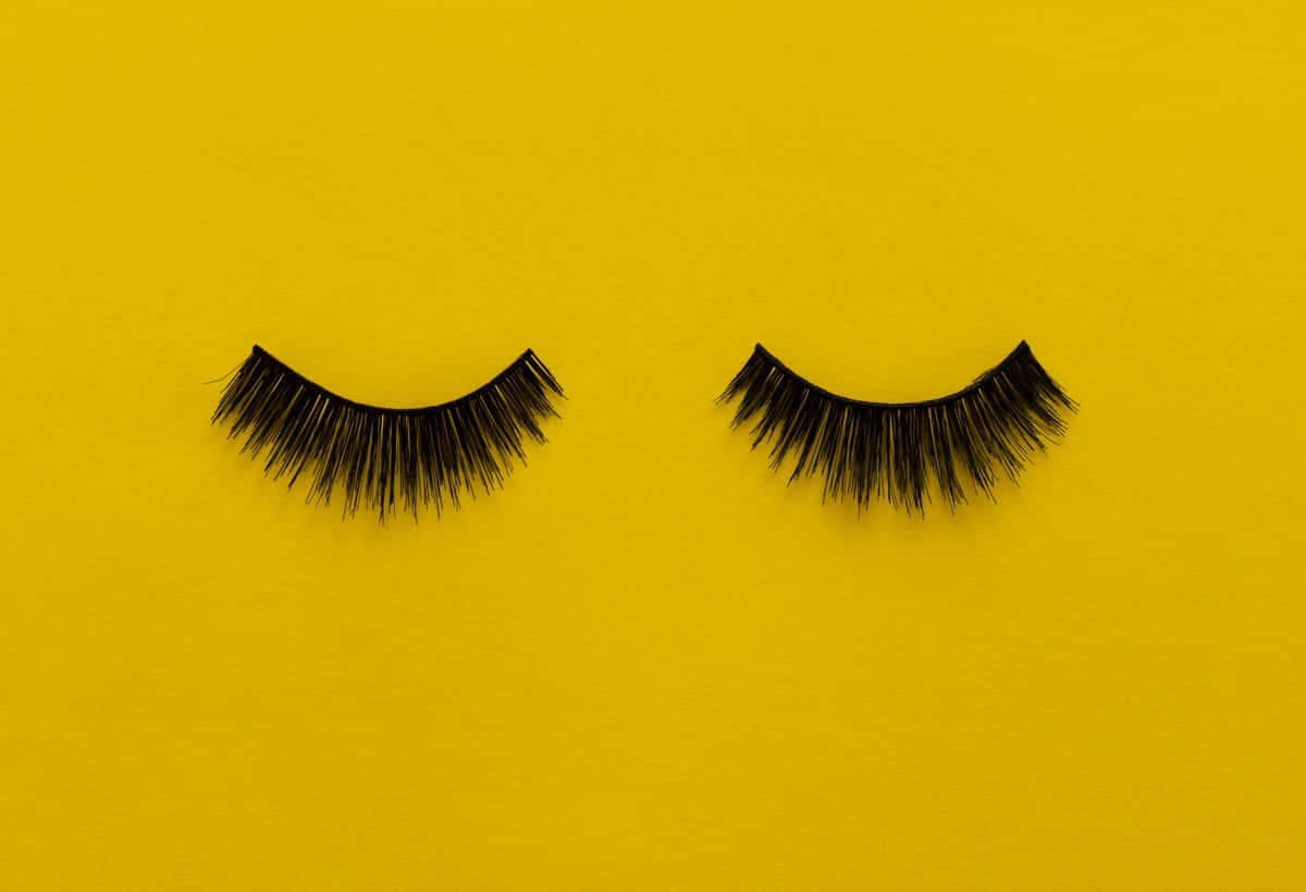 Two Black Lashes On A Yellow Background