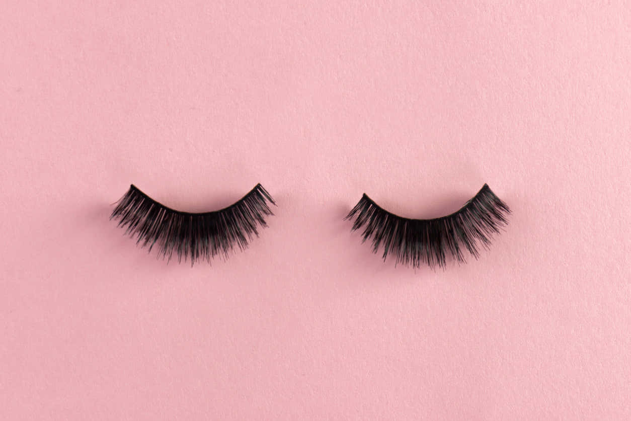 Two False Eyelashes On A Pink Background