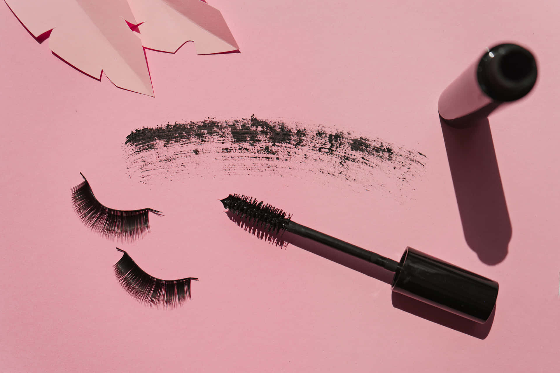 A Pink Background With Black Mascara And Eyelashes