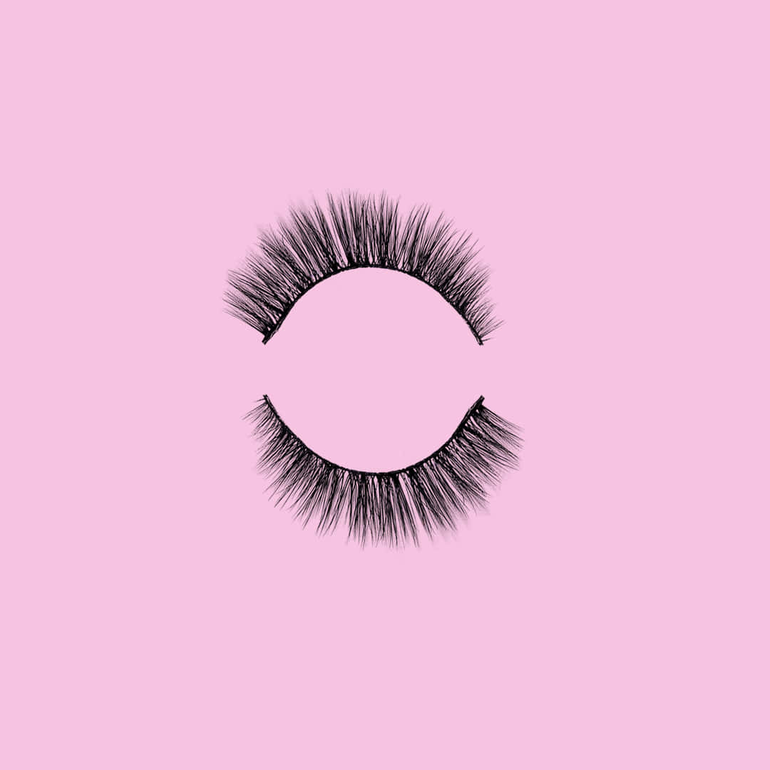 A Pair Of False Lashes On A Pink Background