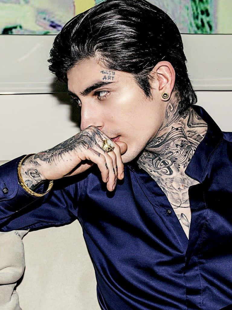 A Man With Tattoos Sitting On A Couch