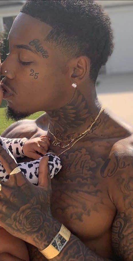 Download A Man Holding A Baby With Tattoos On His Chest