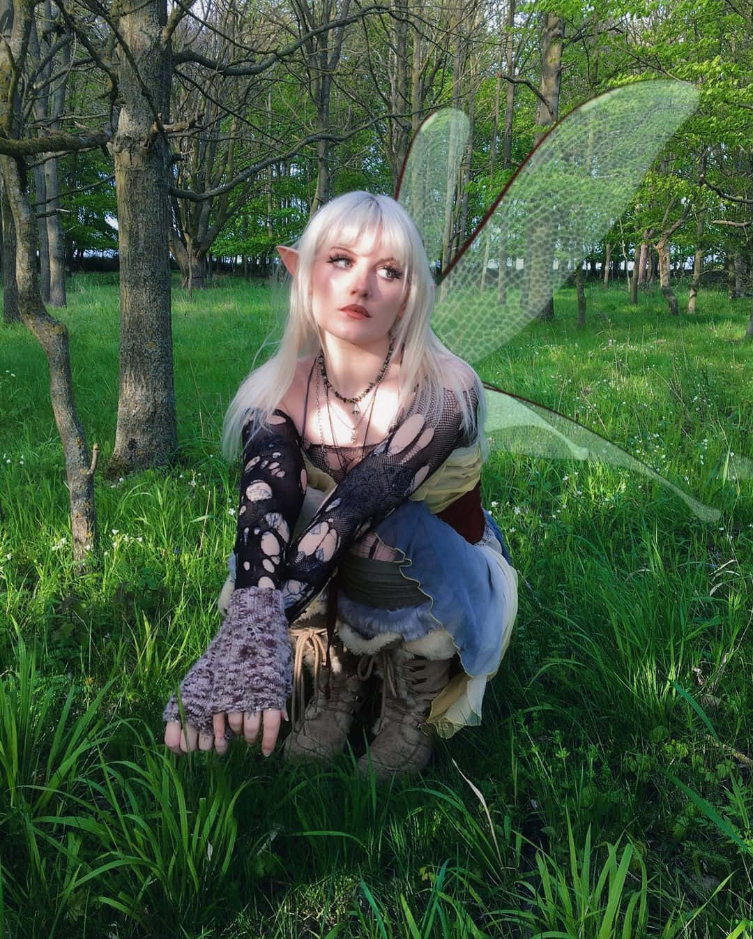A Woman In A Fairy Costume Crouching In The Grass