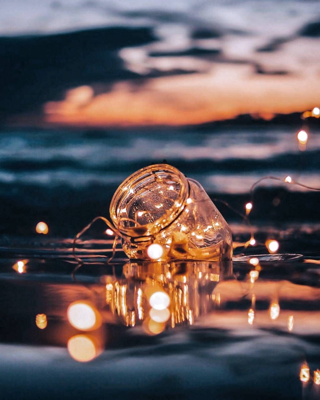 A Glass Jar With Lights Floating In The Water Wallpaper