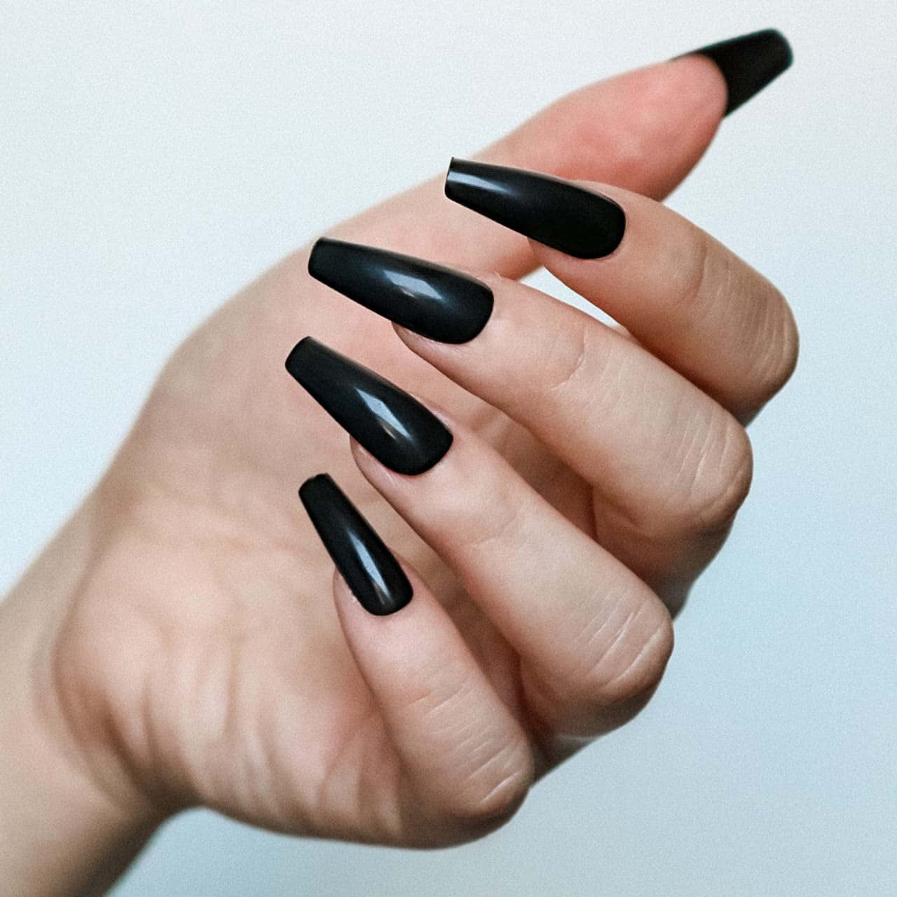 A Woman Holding Black Nails With A Black Tip
