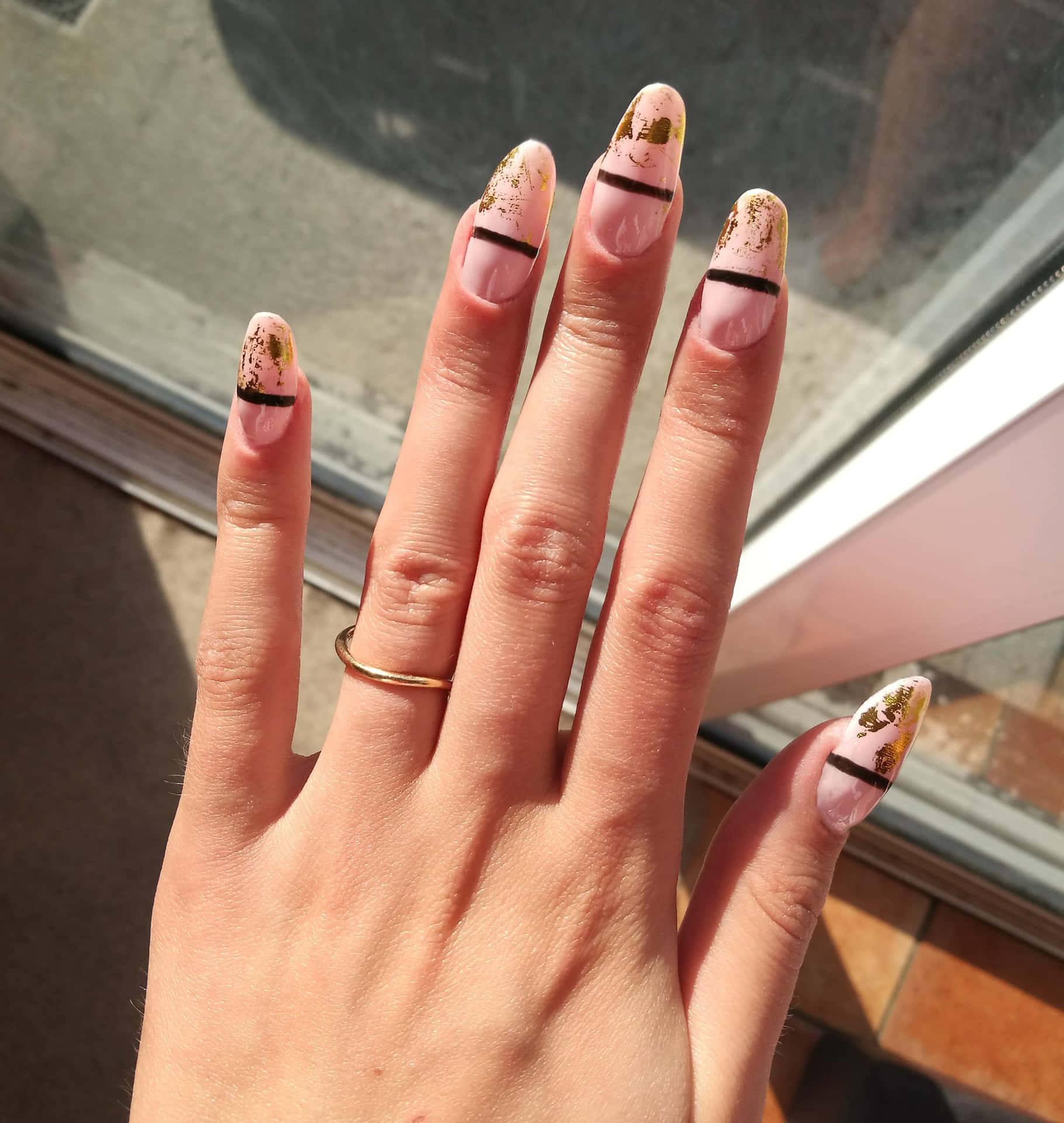 A Woman's Hand With Gold And Black Nails