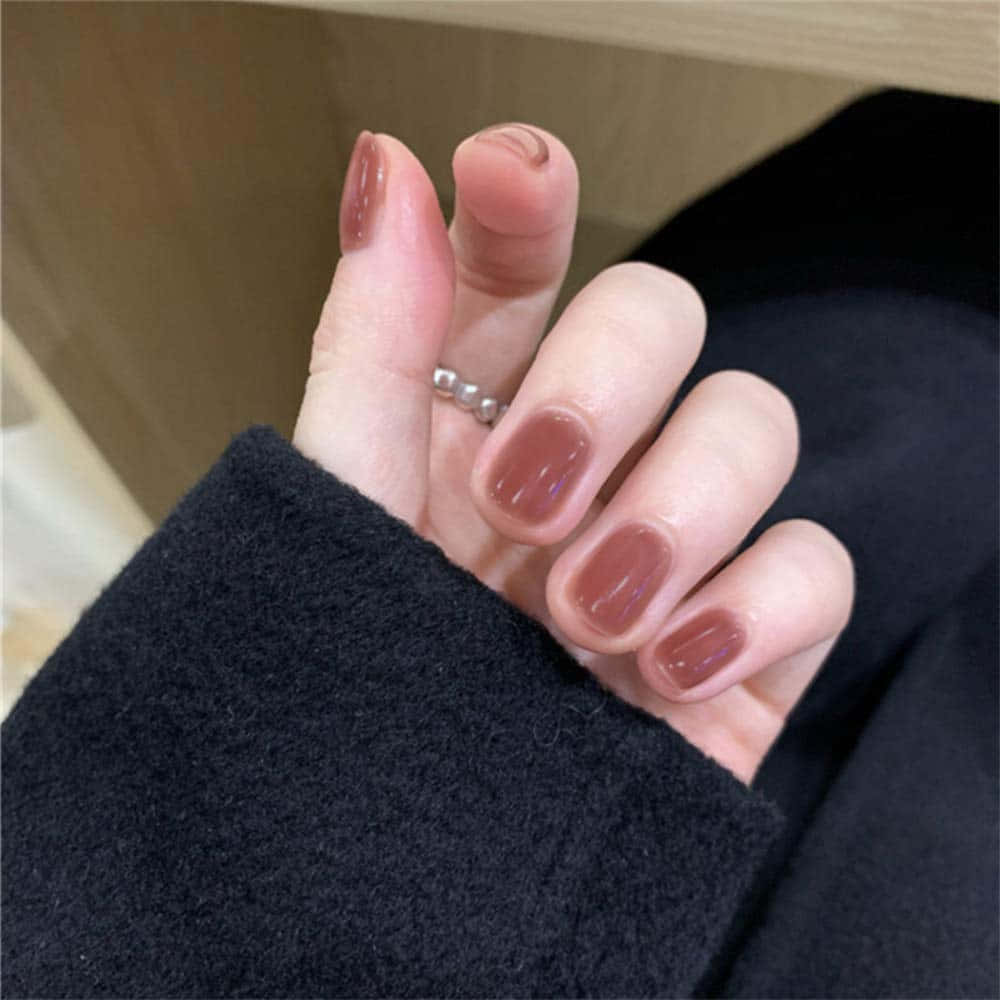 A Woman Holding A Hand With A Brown Nail