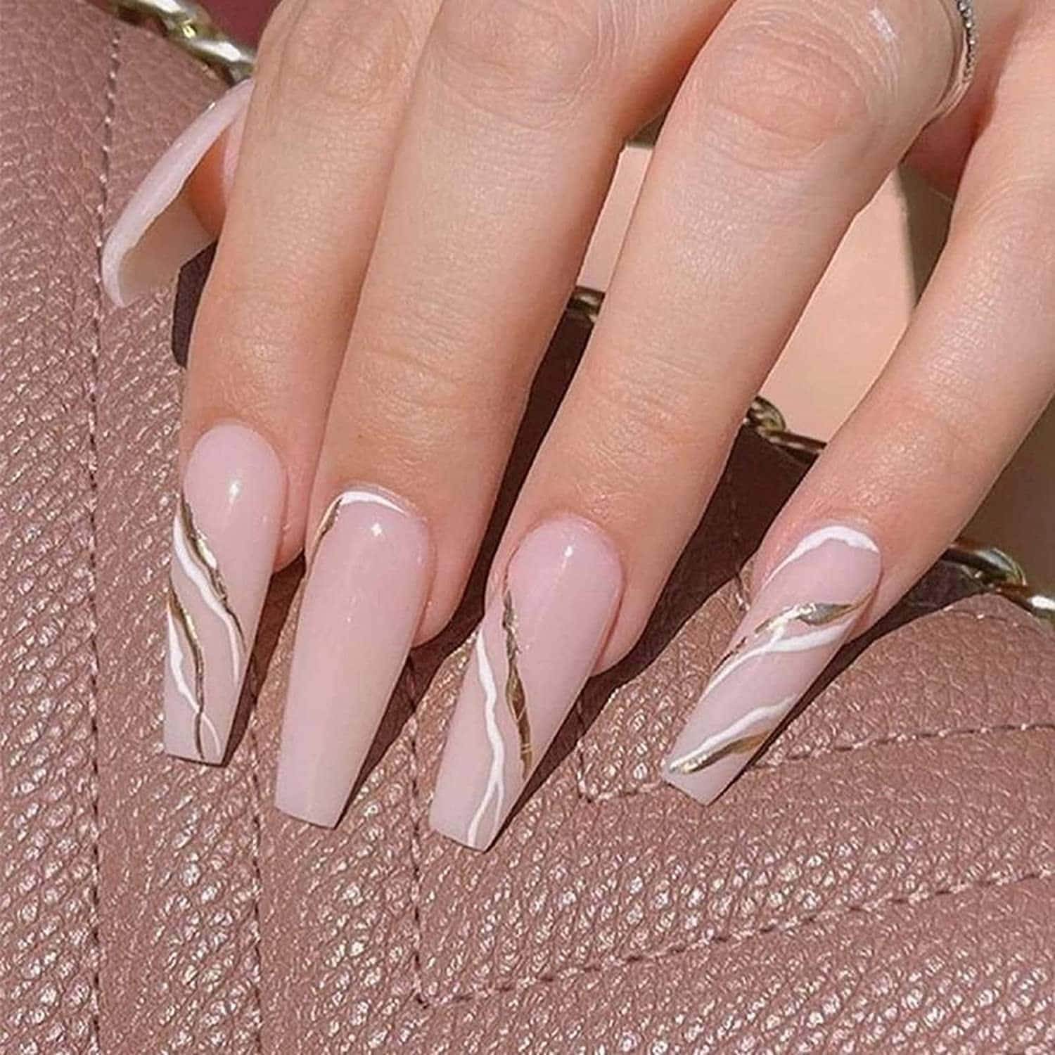 A Woman's Pink Nails With Gold Accents