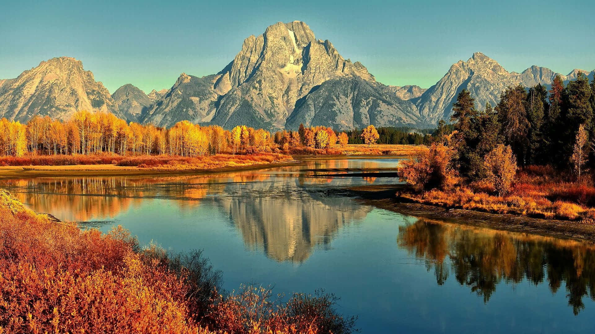 En flod omgivet af bjerge i efterårsfarver Wallpaper