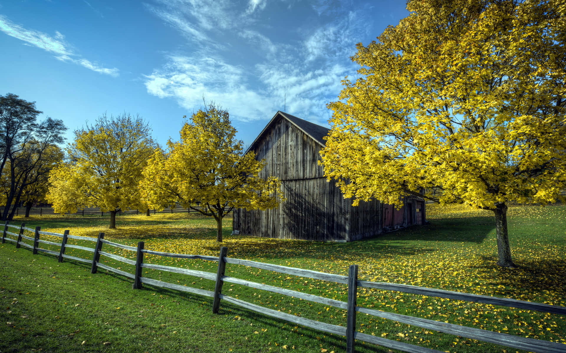 A picturesque barn nestled amidst the vibrant fall foliage Wallpaper