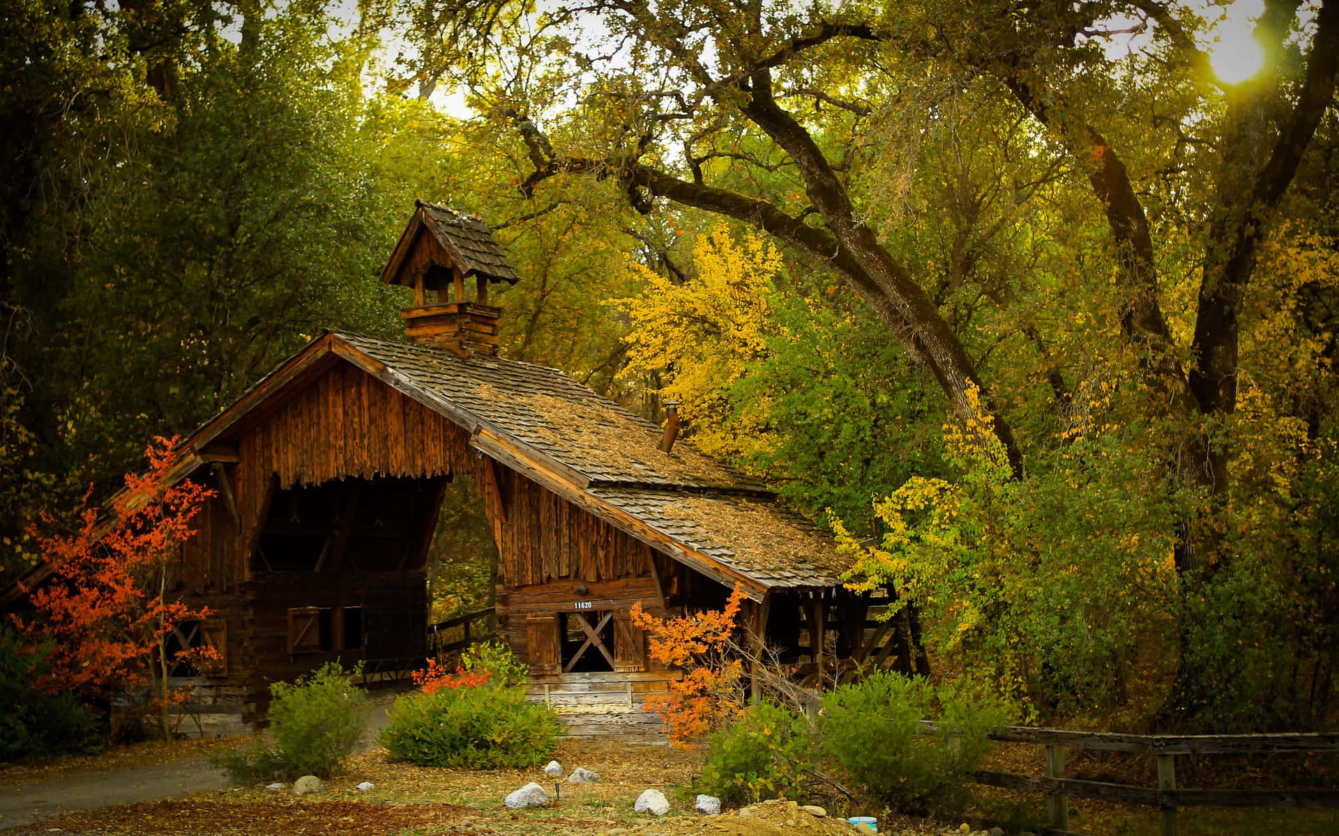 A beautiful rustic barn surrounded by vibrant foliage during the fall season. Wallpaper
