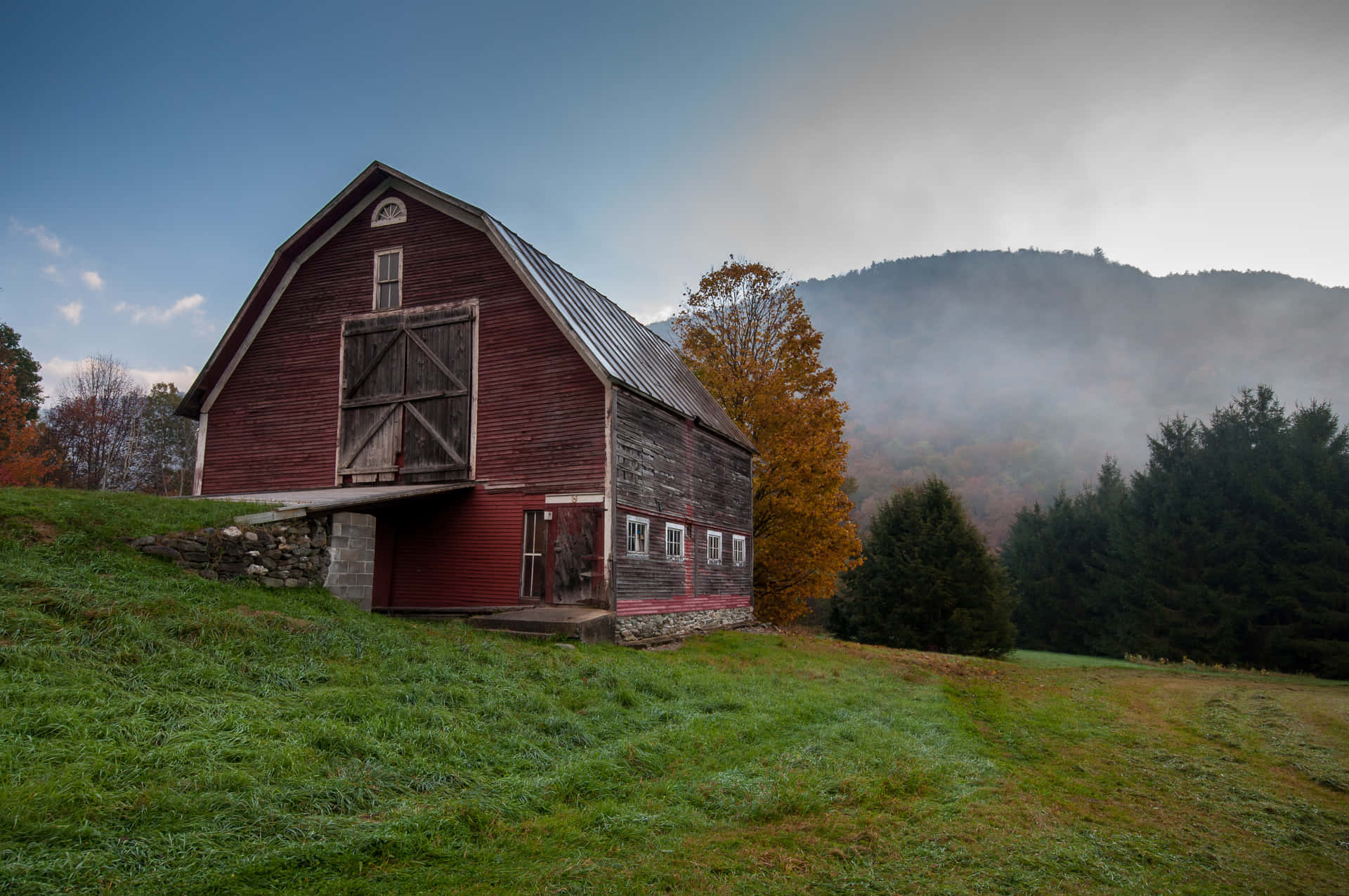 A rustic barn surrounded by a vibrant autumn landscape Wallpaper