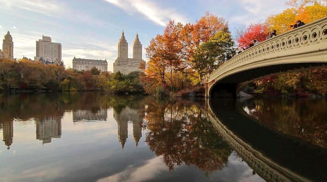 A Scenic Fall Bridge Over Tranquil Waters Wallpaper