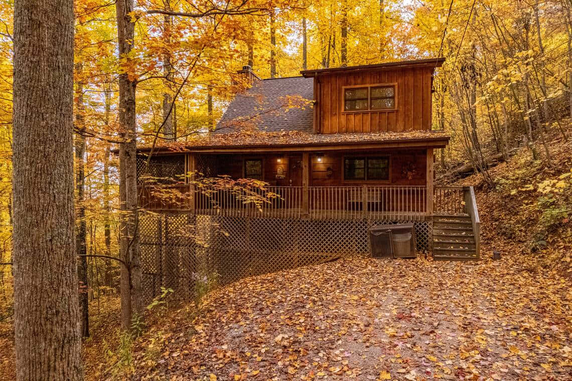 Cozy Fall Cabin Surrounded by Autumn Foliage Wallpaper