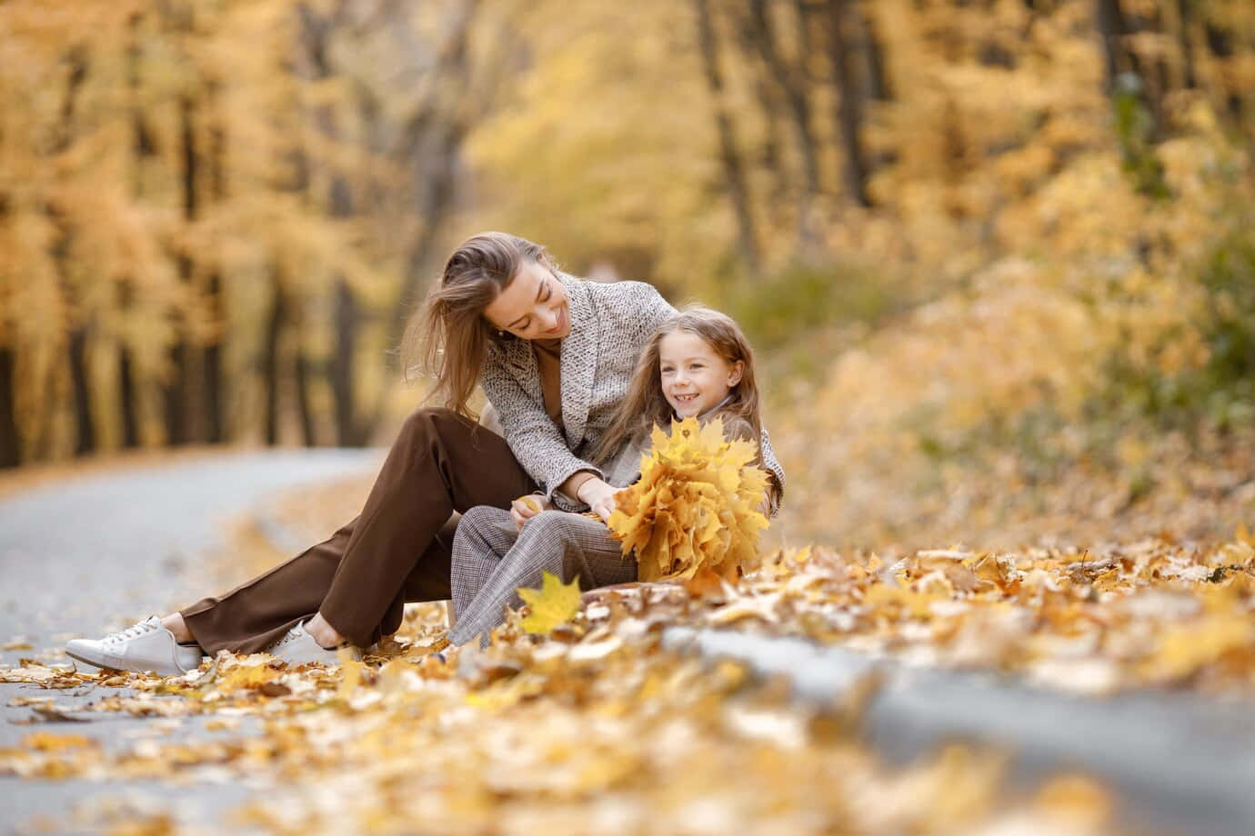 A Mother And Daughter Sitting On The Road In Autumn