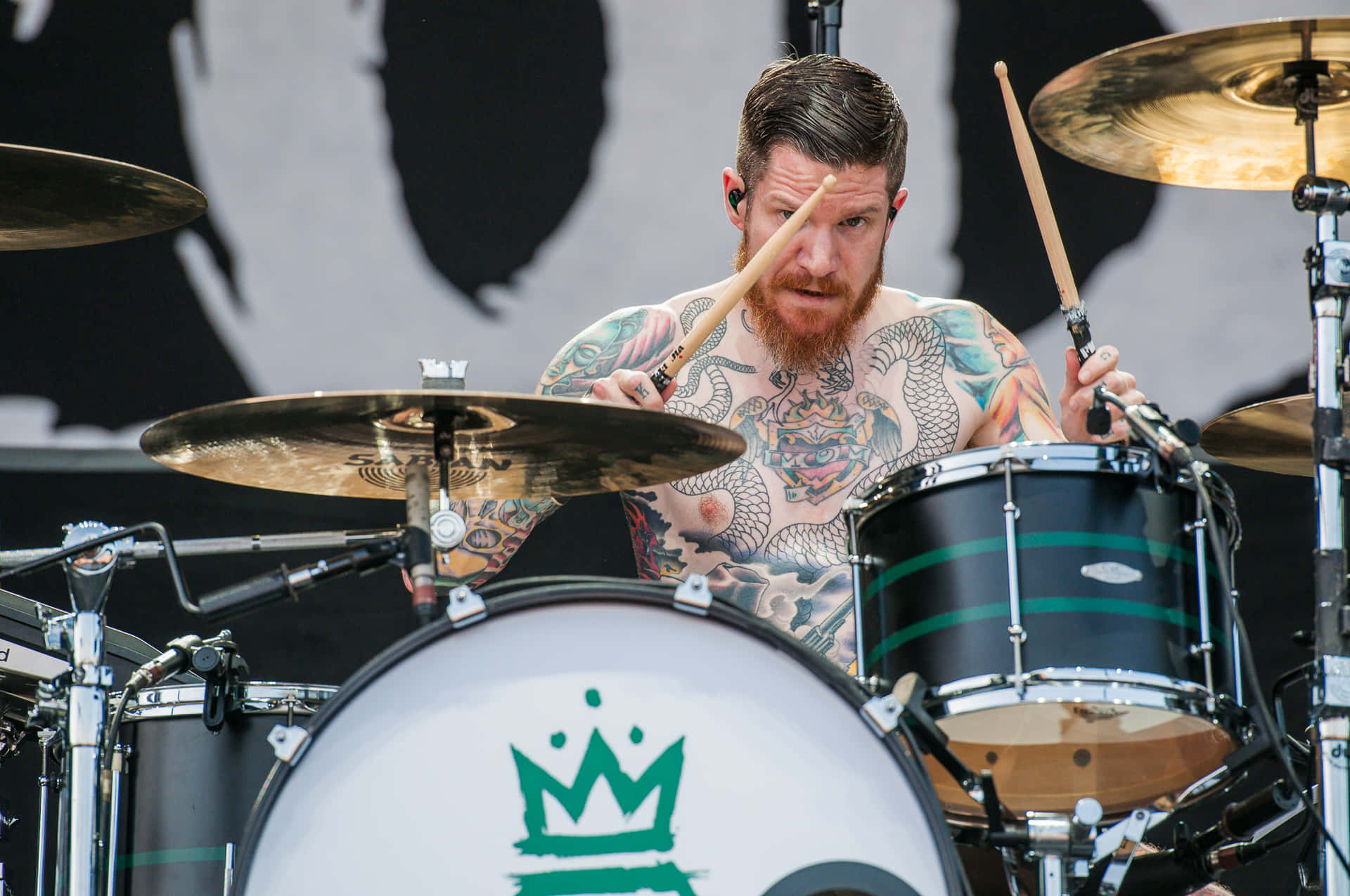 A Man With Tattoos Playing Drums On Stage Wallpaper