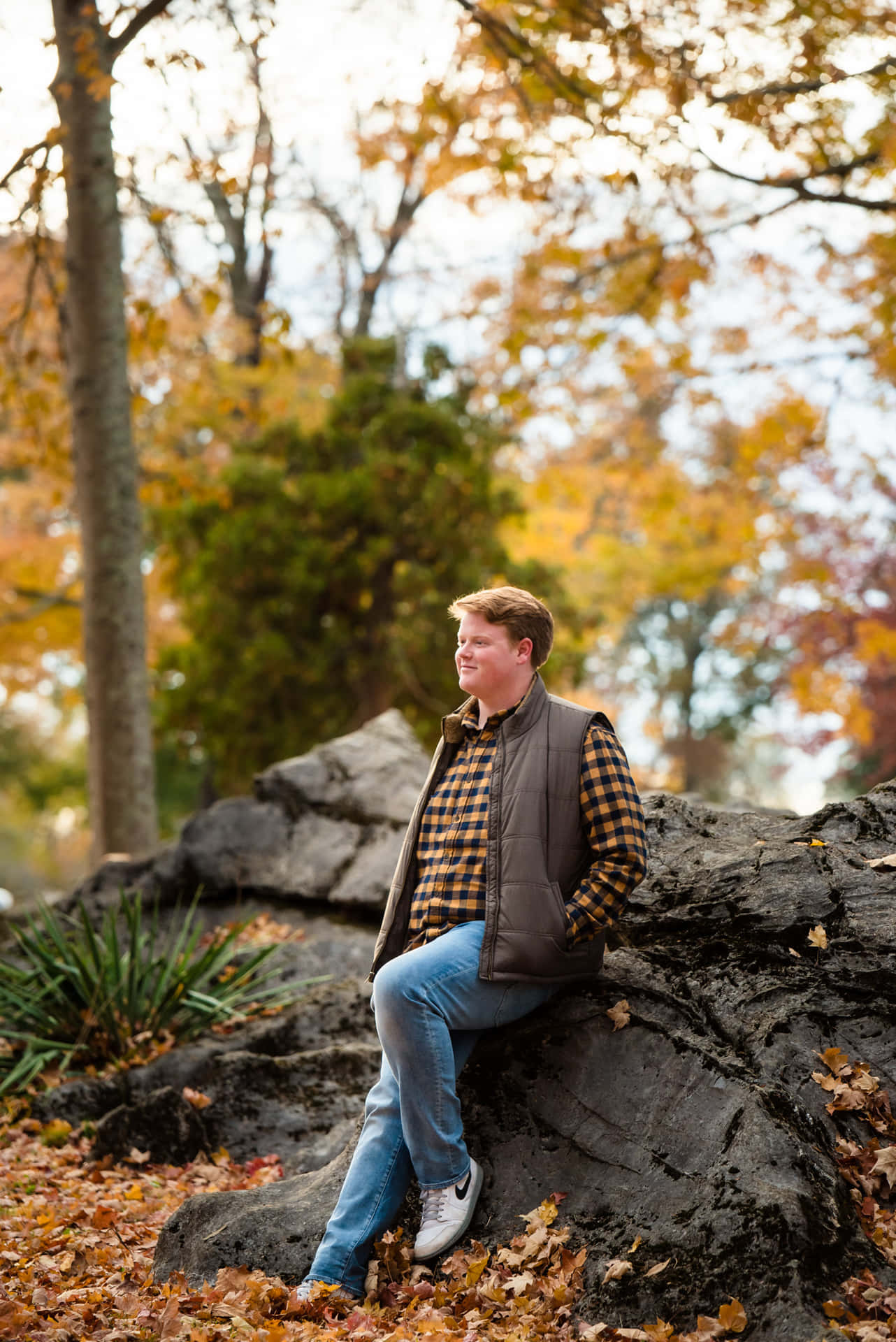 En mand sidder på en klippe om efteråret.