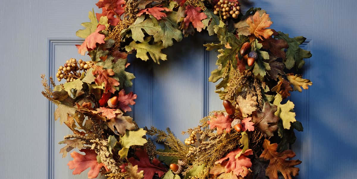 Beautiful Fall Wreath Adorning a Rustic Wooden Door Wallpaper