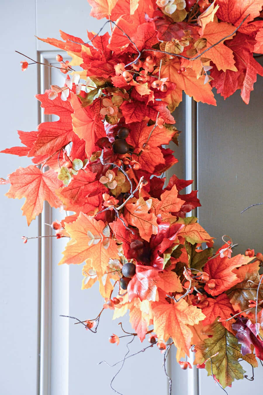 Vibrant Fall Wreath Adorning a Rustic Wooden Door Wallpaper