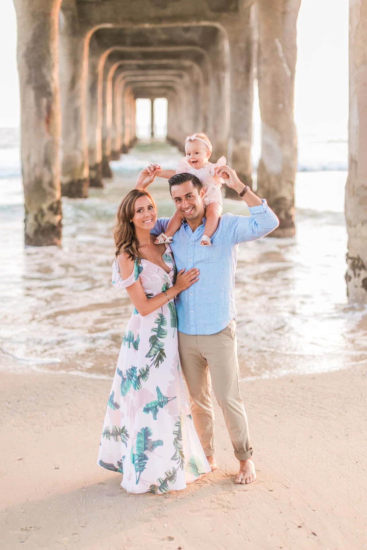 A Family Poses Under The Pier With Their Baby