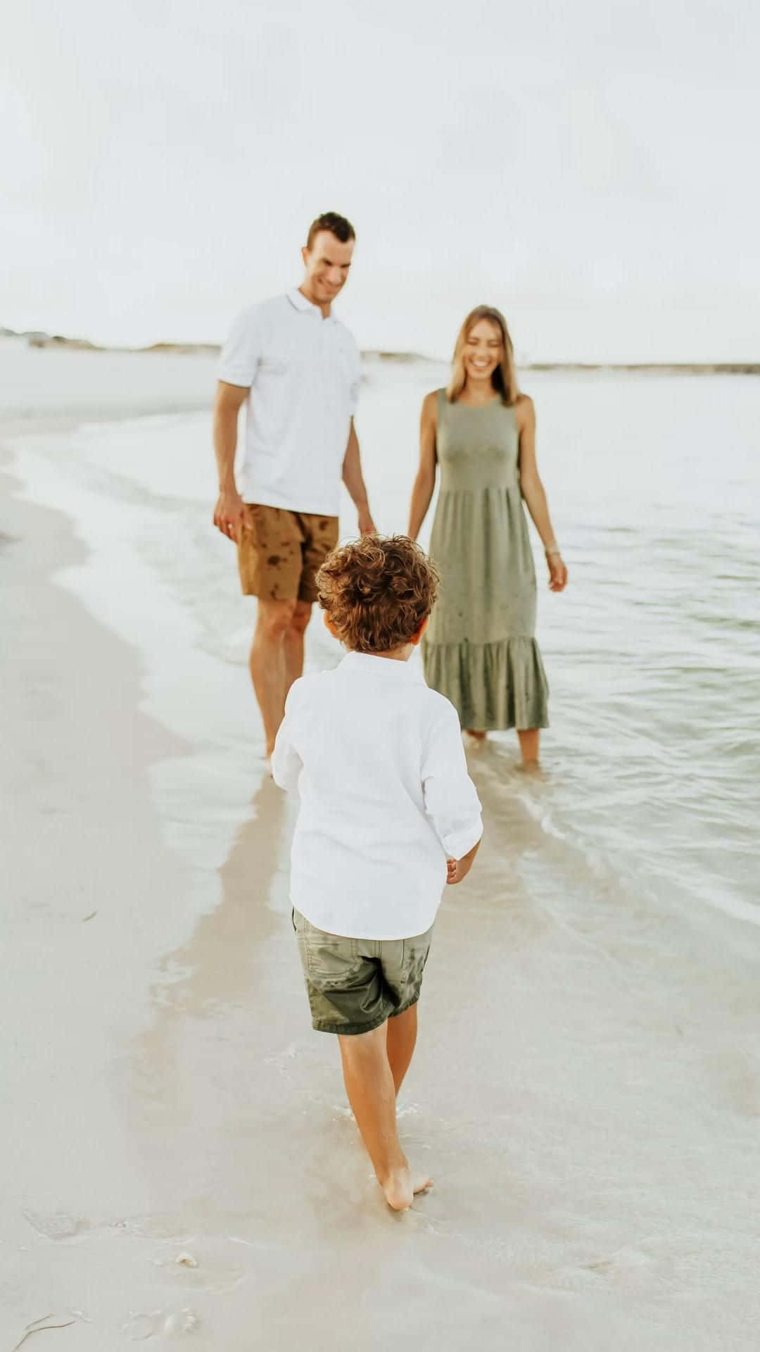 Familien går på stranden med en ung dreng.