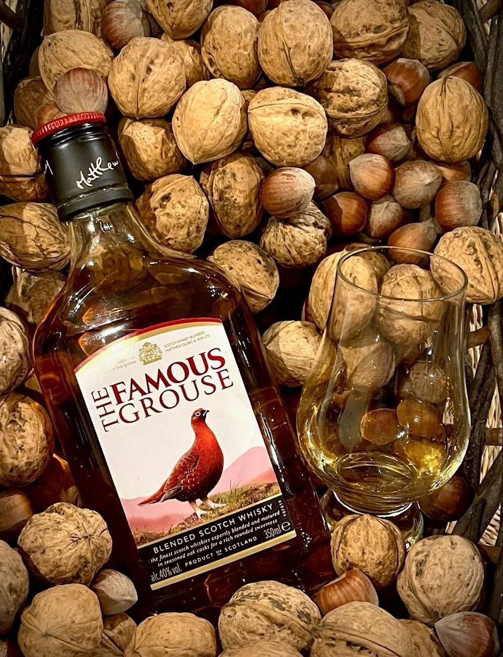 A bottle of the world-famous Blended Scotch, Famous Grouse whisky against a warm backdrop Wallpaper