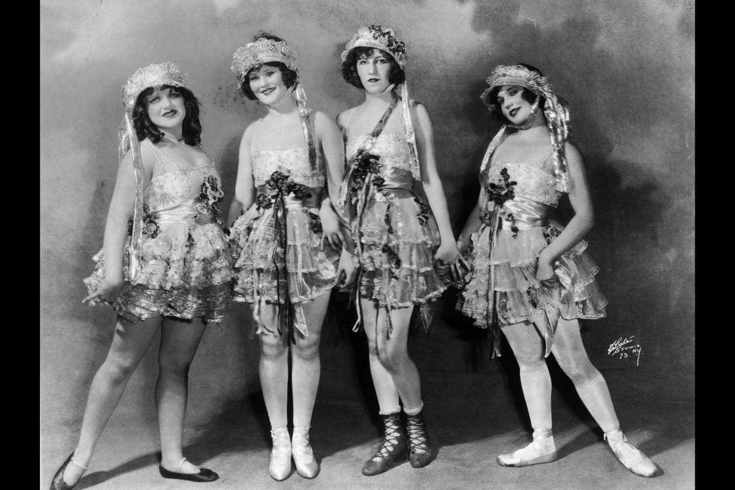Vierfrauen Mit Hüten Und Kleidern Posieren Für Ein Foto.