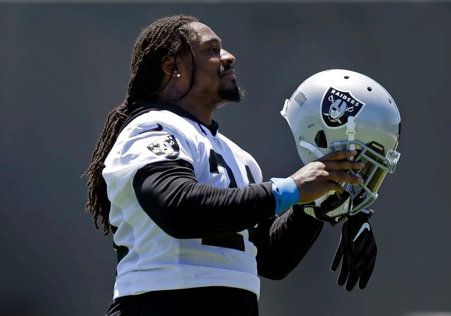 A Football Player With Dreadlocks Is Holding A Helmet