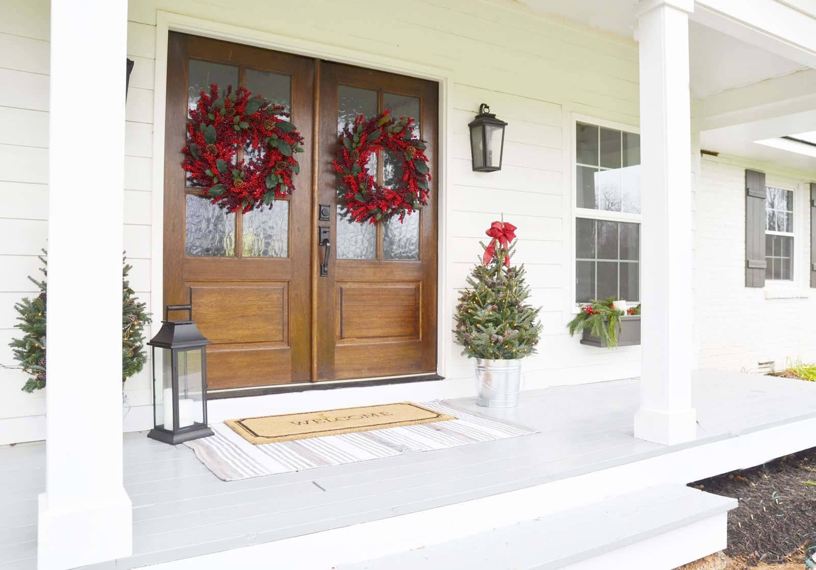 A White Front Porch With Wreaths And Potted Plants Wallpaper