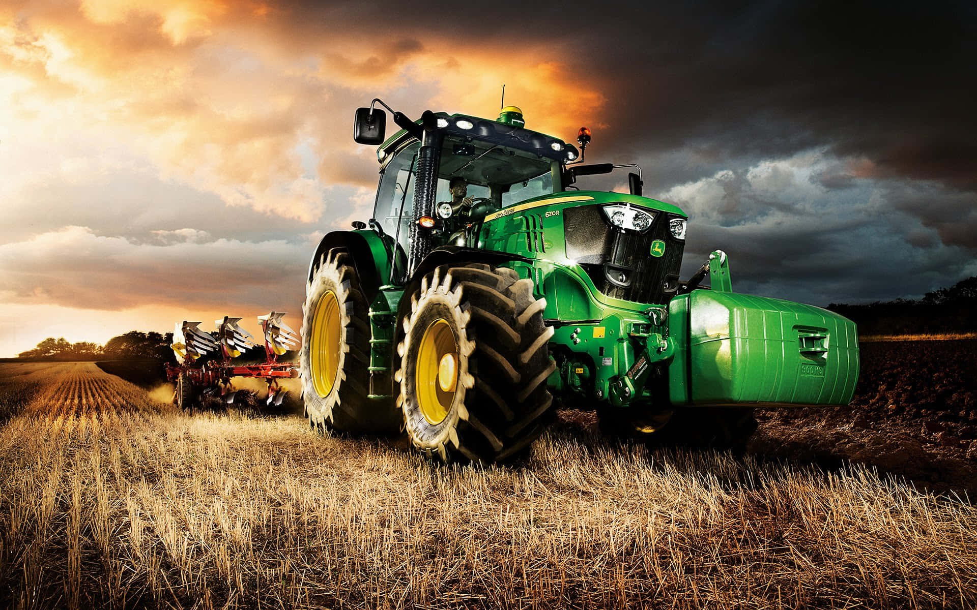 A Green Tractor Driving In A Field Wallpaper