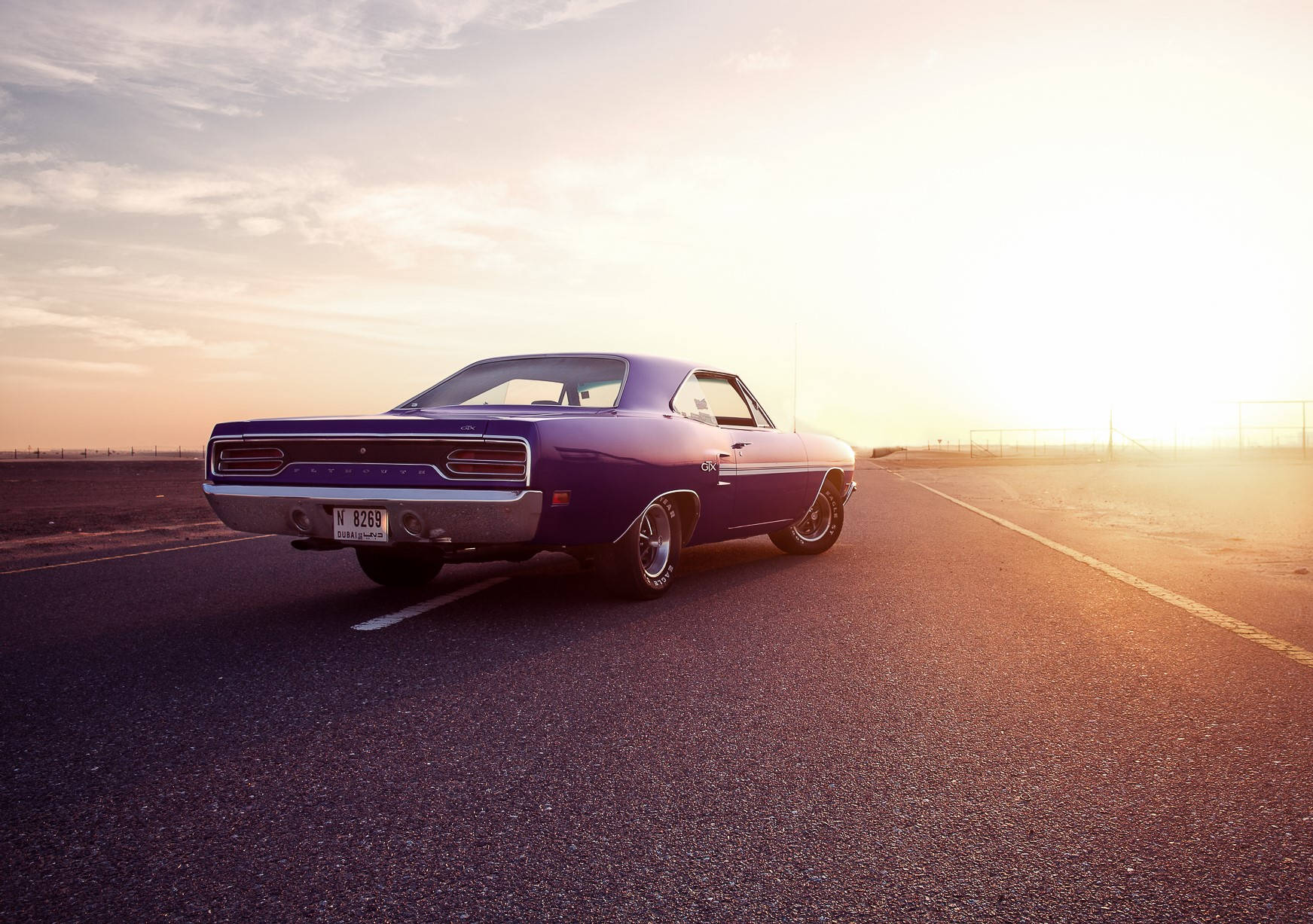 A Purple Car Is Driving Down The Road Wallpaper