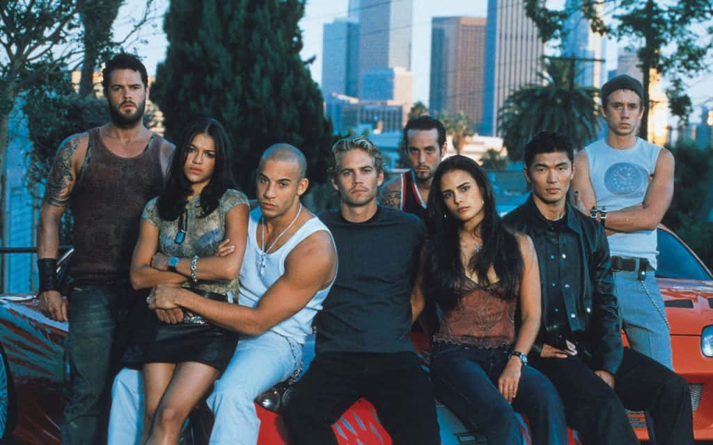 The Cast Of Fast And Furious Posing On A Red Car