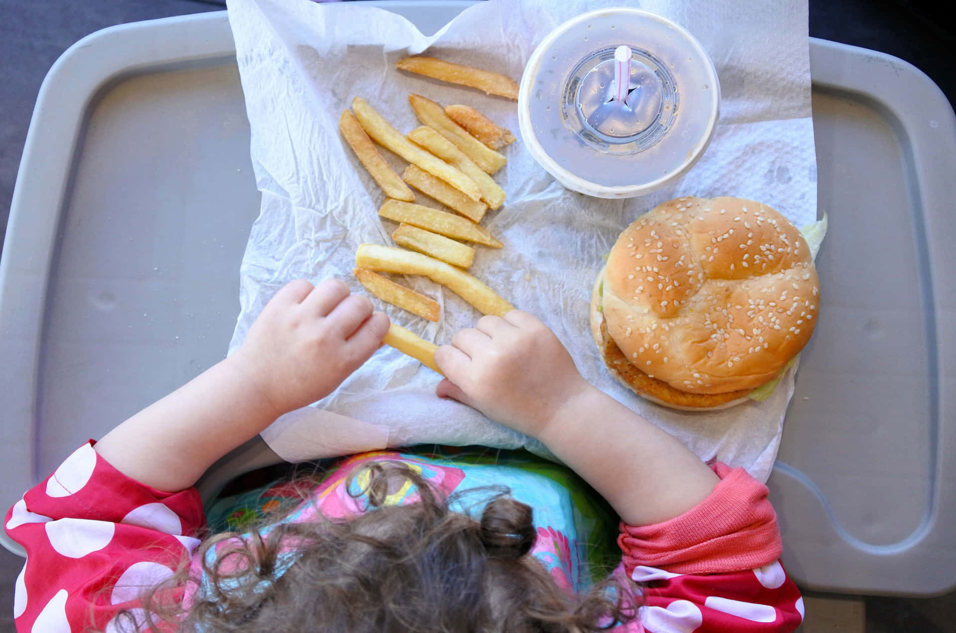A Child Eating A Hamburger And Fries