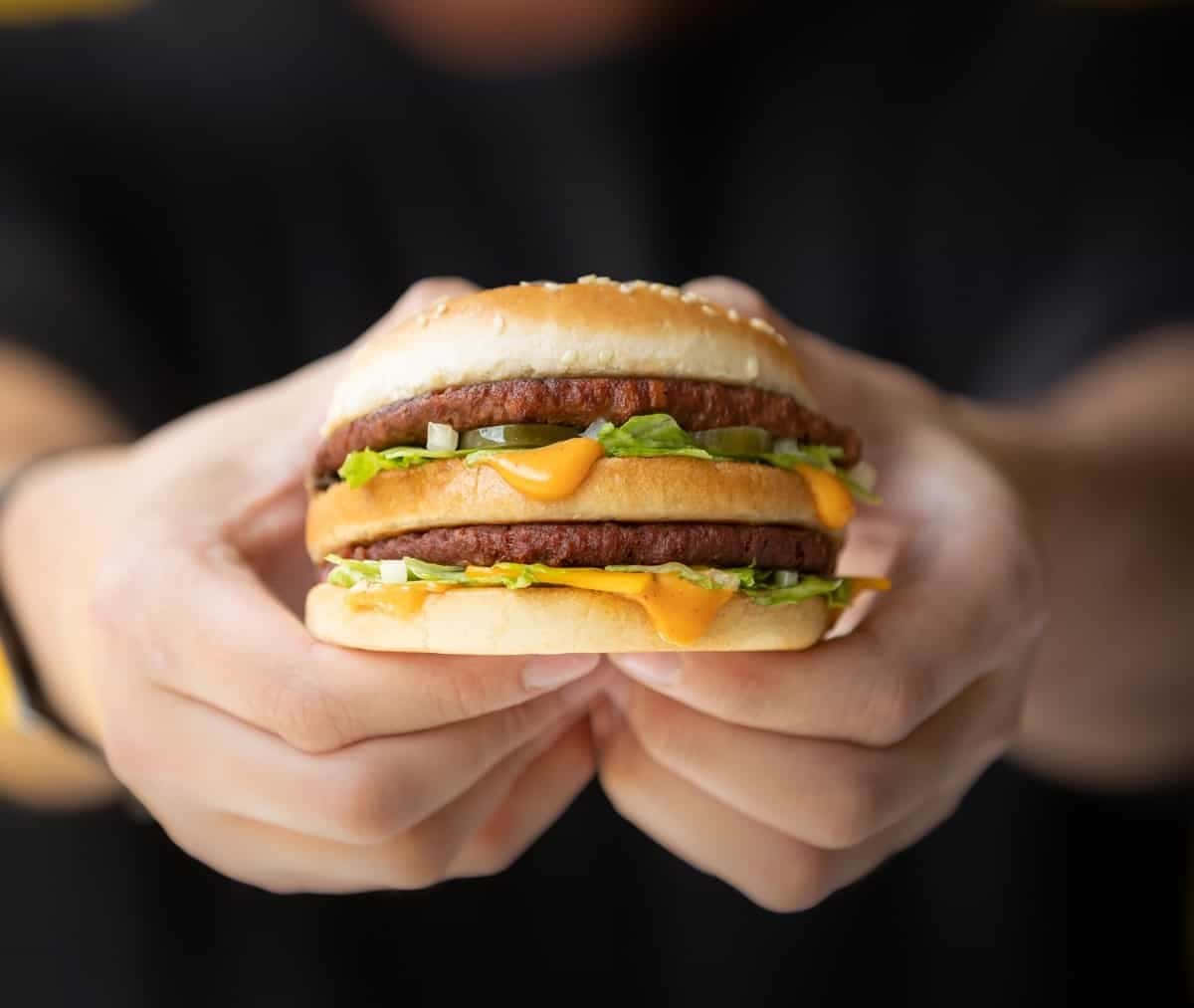 A Person Holding Up A Mcdonald's Hamburger